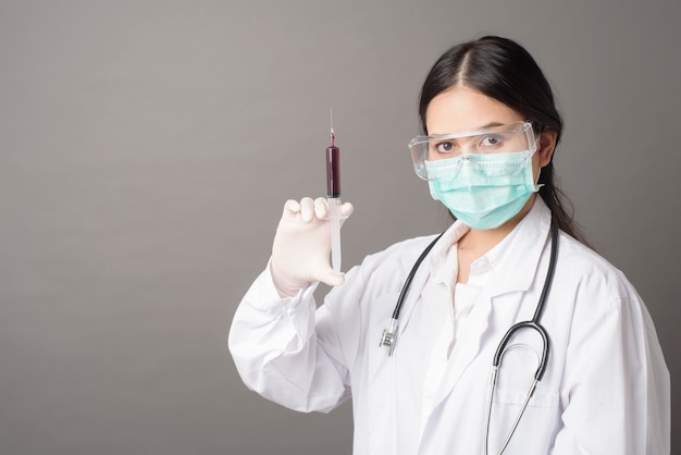 Doctor woman with surgical mask is holding hypodermic syringe