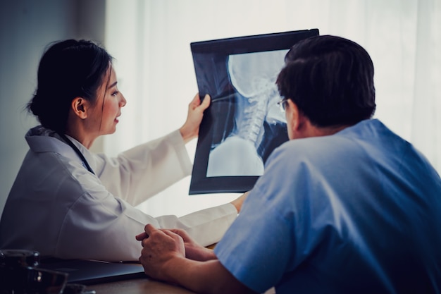 Doctor women holding x-ray flim show old patient men Talking with Medical  in clinic office