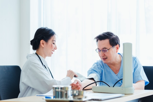 Doctor women measuring blood at patient men talking with medical in clinic office