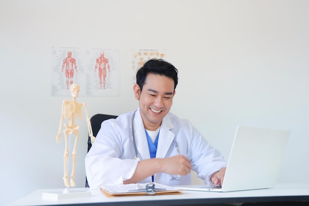 Doctor working on laptop at the desk in clinic.