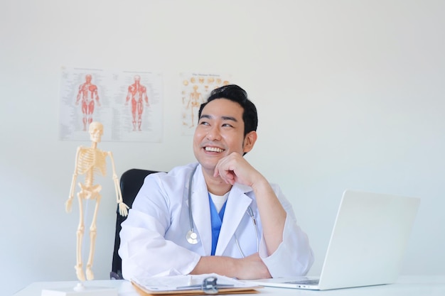 Photo doctor working on laptop at the desk in clinic.