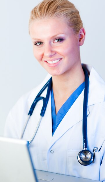 Doctor working on a laptop looking at camera