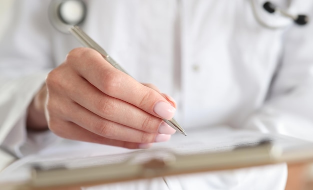 Doctor writes down patient medical history with pen on card