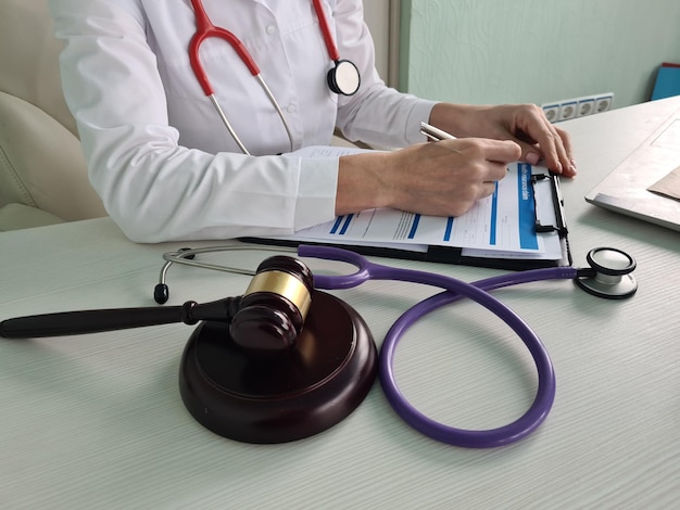 Doctor writes resignation letter near gavel on sound block