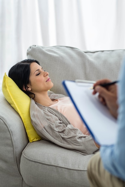 Doctor writing on clipboard while consulting pregnant woman at home