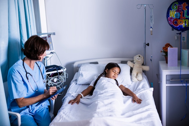 Doctor writing on clipboard while looking at patient