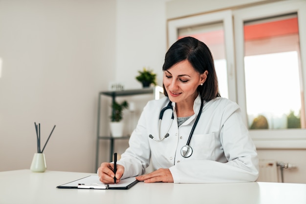 Doctor writing on clipchart in medical office.