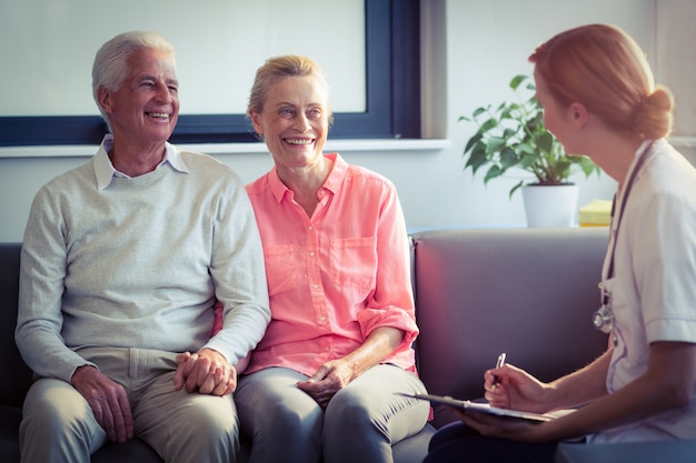 Doctor writing medical report of senior couple