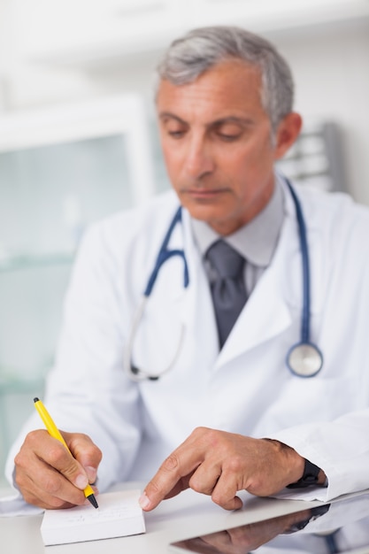 Doctor writing on a notepad at his desk