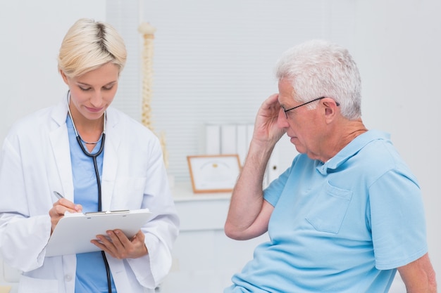 Doctor writing prescription for senior patient