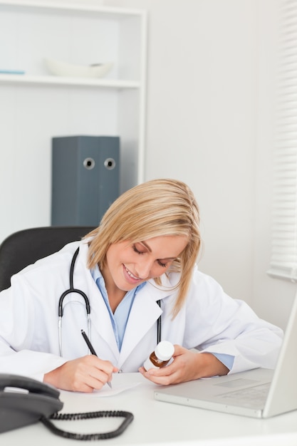 Doctor writing something down while holding medicine