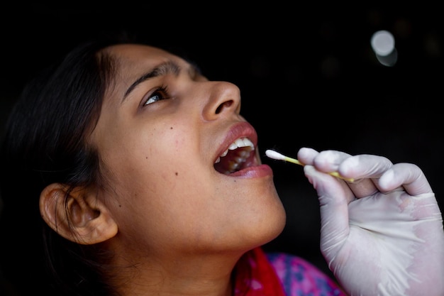 Doctor39s hand taking Saliva test from young woman39s mouth with Cotton Swab Coronavirus Throat sample Collection Closeup views