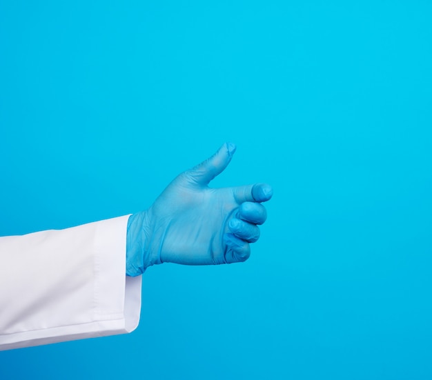 Foto la mano del dottore indossa un guanto di gomma sterile blu che regge un oggetto