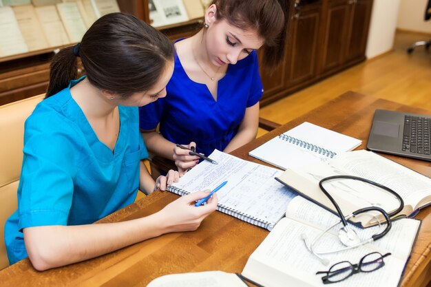 Foto tesi di dottorato. sfondo uno studente di medicina per i libri di testo nella scuola per infermieri.