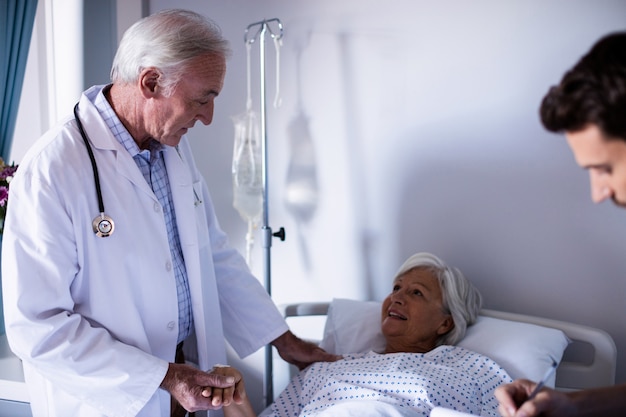 Doctors comforting senior patient on bed