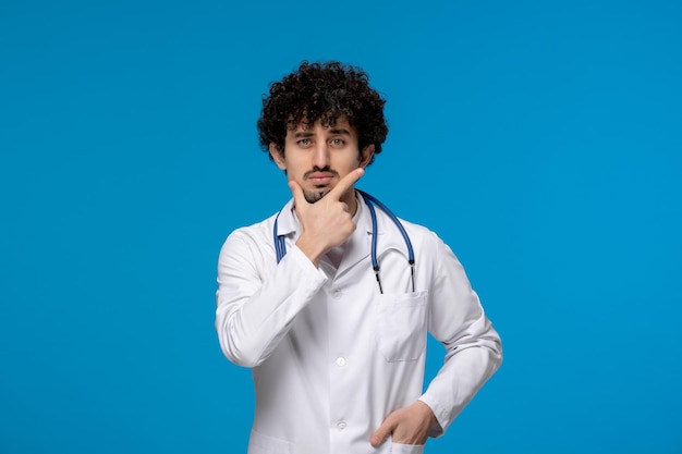 Doctors day curly handsome cute guy in medical uniform thinking and looking seriously