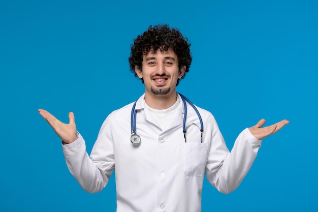 Doctors day curly handsome cute guy in medical uniform waving hands and smiling