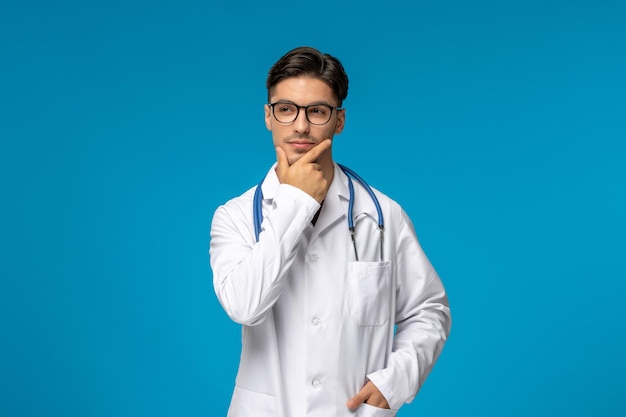 Doctors day handsome brunette cute guy in medical gown thinking and looking far