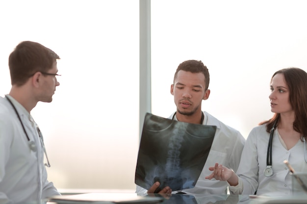 Doctors discuss the x-ray of the patient sitting at the table . the concept of health