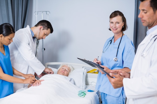 Doctors examining patient in ward