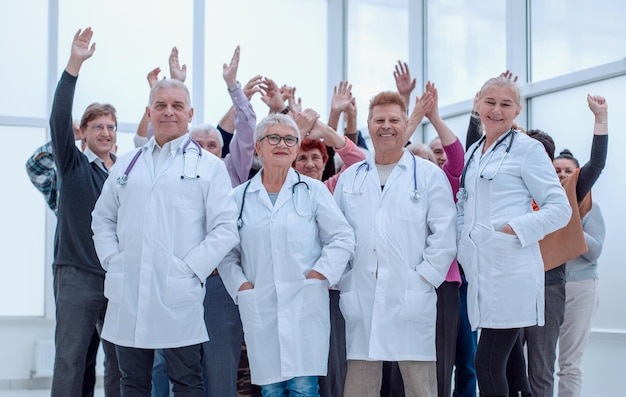 Doctors and a group of seniors in full growth indoors hands up