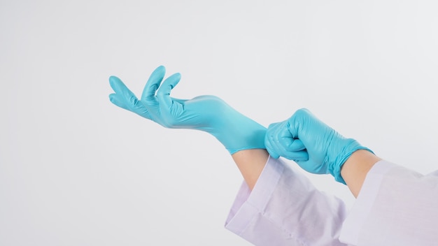 医師の手は白い背景の上の青いラテックス手袋を引っ張っています
