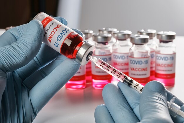 Doctors hand in protective gloves holds vaccine vial and fill syringe