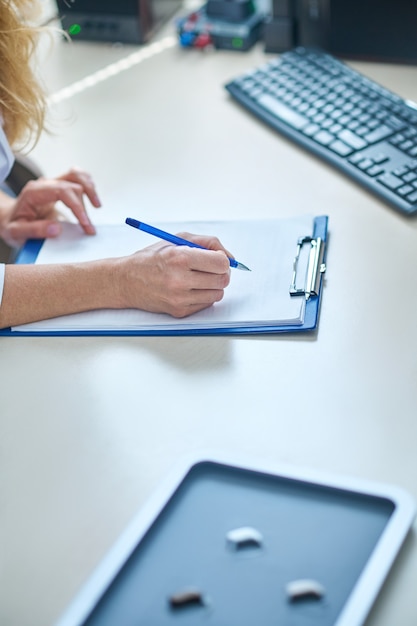 Doctors hand writing note in work notebook