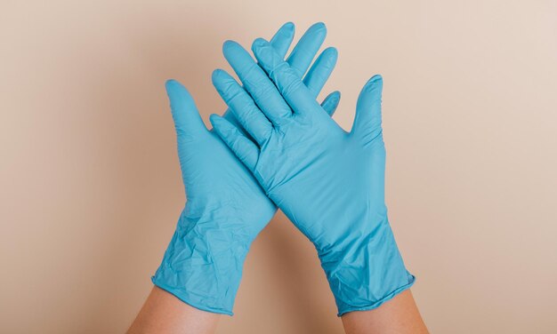 Doctors hands in medical gloves in shape of heart on blue background