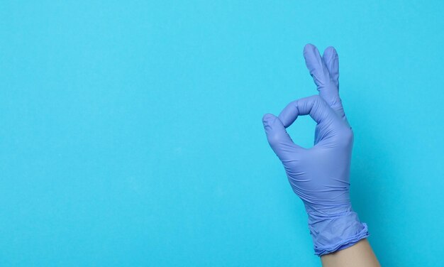 Doctors hands in medical gloves in shape of heart on blue background