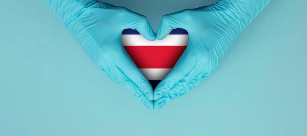 Doctors hands wearing blue surgical gloves making hear shape symbol with costa rica flag