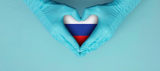 Doctors hands wearing blue surgical gloves making hear shape symbol with russia flag