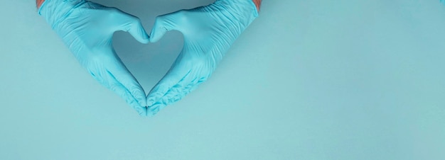 Doctors hands wearing blue surgical gloves making hear shape symbol