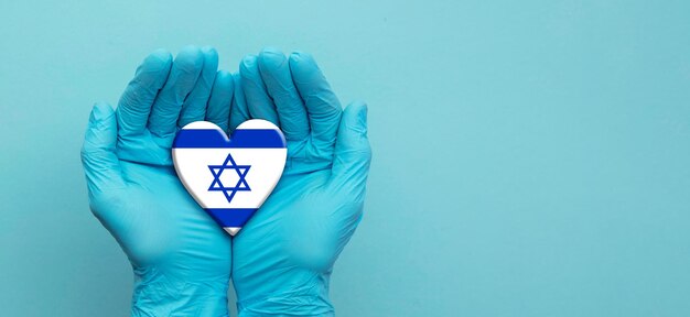 Doctors hands wearing surgical gloves holding israel flag heart