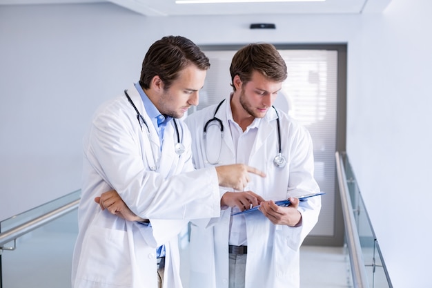 Doctors having discussion on clipboard in corridor