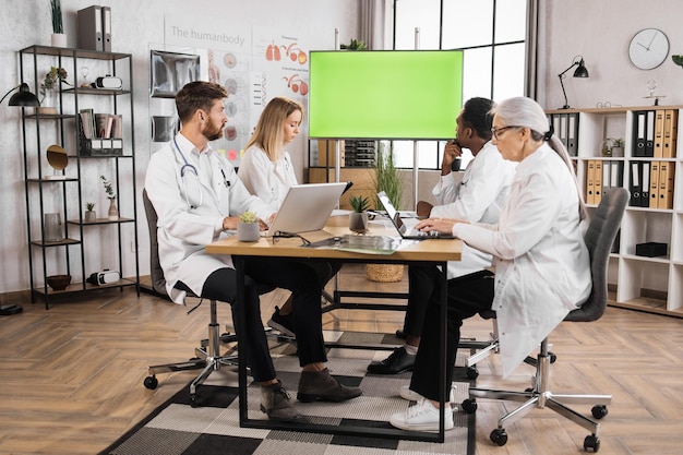 Doctors looking on monitor with green screen at clinic