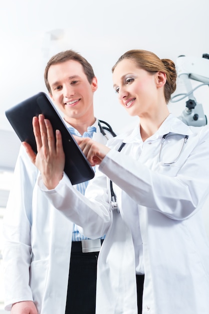 Doctors - male and female - discussing test reports that show on their tablet Computer