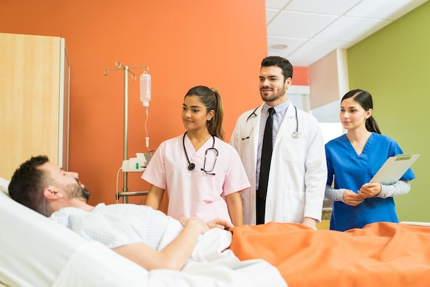 Doctors and nurse looking at sick mid adult patient while standing in hospital