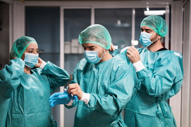 Doctors and nurse preparing to work in hospital for surgical operation during coronavirus pandemic