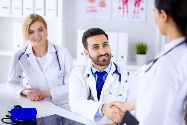 Doctors in the office communicate and shake hands.