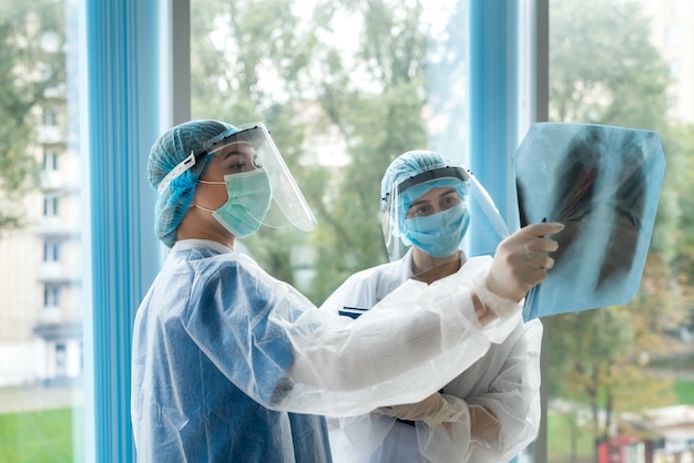 Doctors in protective clothing during a coronavirus pandemic discuss pneumonia treatment