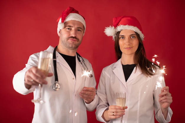 doctors in Santa Claus hats cheering with champagne glasses and holding sparklers