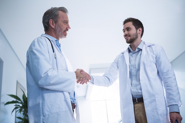 Doctors shaking hands while interacting in corridor