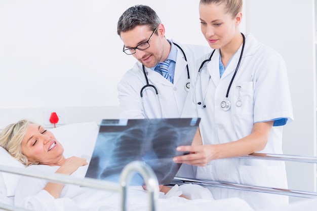 Doctors showing x-ray to patient in bed