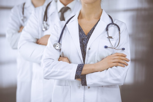 Doctors standing as a team with arms crossed in clinic. Medical help, insurance and medicine concept.