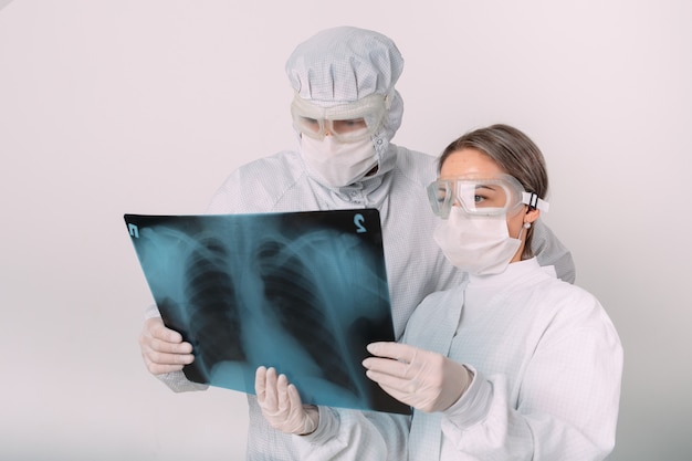 Doctors standing on white background examine x-ray for pneumonia of a Covid-19 patient in the clinic. Coronavirus concept.