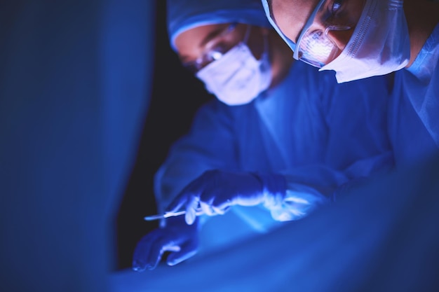 Doctors team in surgery in a dark background