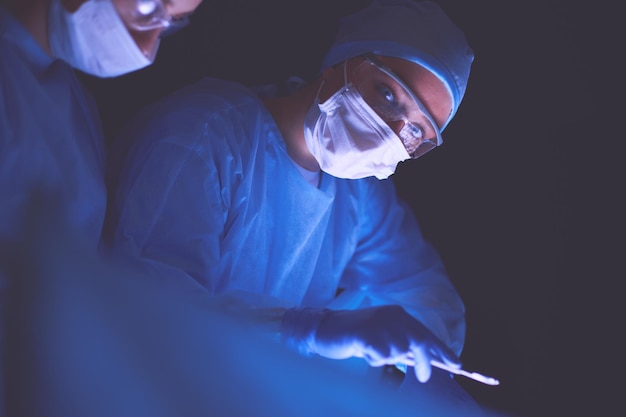 Doctors team in surgery in a dark background