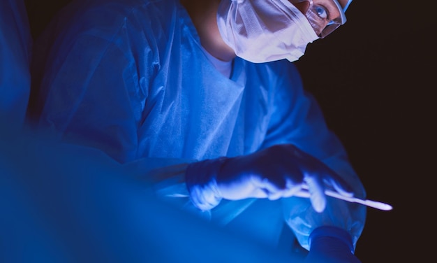 Doctors team in surgery in a dark background