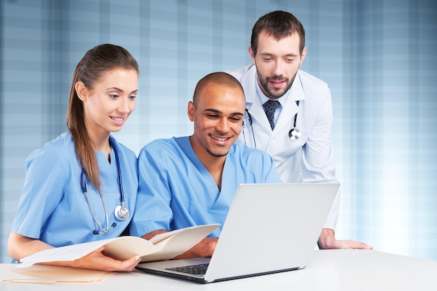 Doctors team talking expertise in hospital by laptop